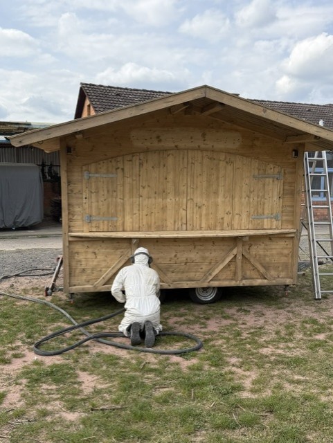 Mitarbeiter von Strahlkraft Langen kniend beim Sandstrahlen der Unterkante – Holz bereits auf Naturton freigestrahlt